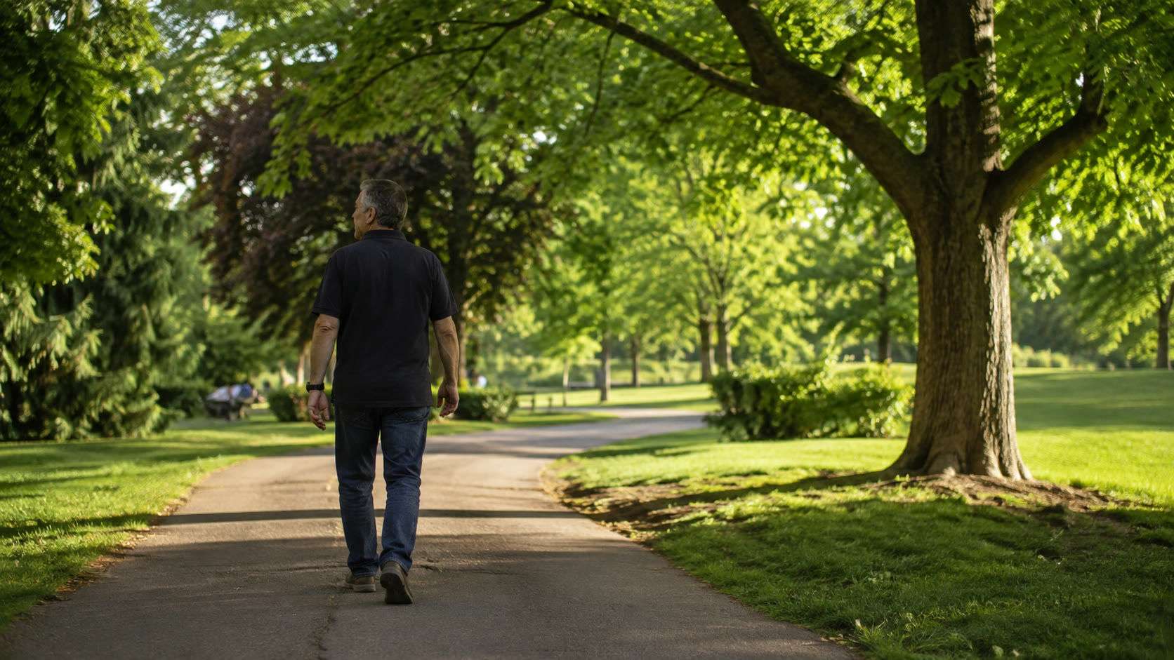 Középkorú ember hétköznapi ruhában sétál egy napsütötte parkban